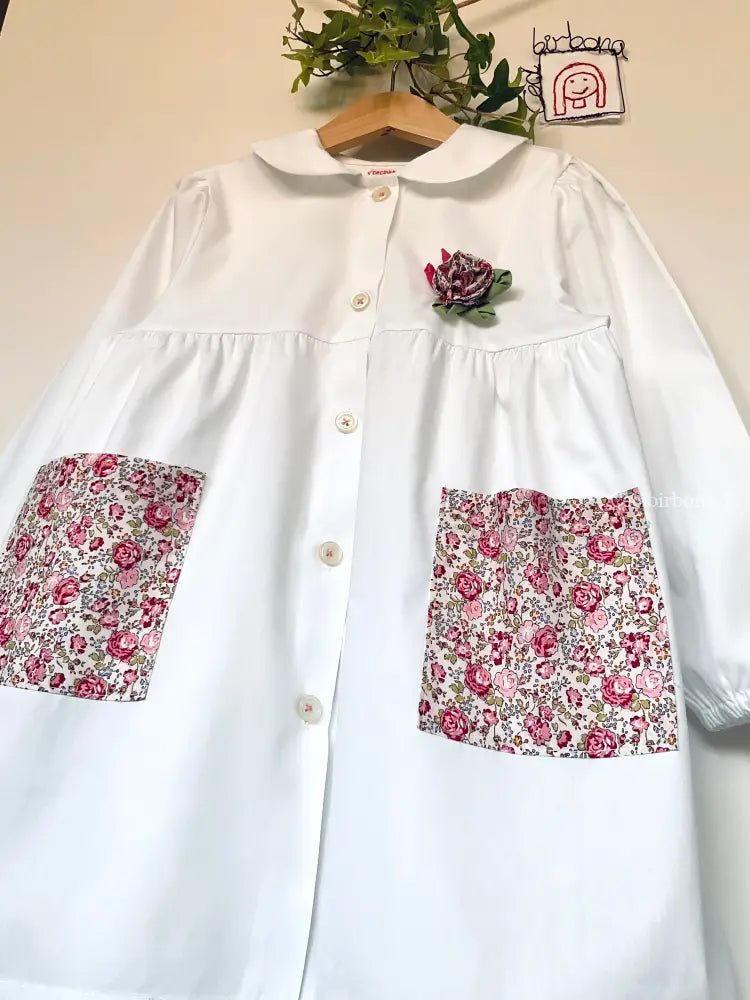Il grembiulino con le rose e i lillà - Grembiule bianco per asilo con tasche a fiorellini rosa e colletto tondo