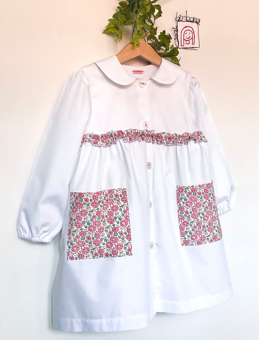 Le tablier à fleurs roses et myosotis - Tablier de maternelle en coton blanc avec volants et poches à fleurs roses.